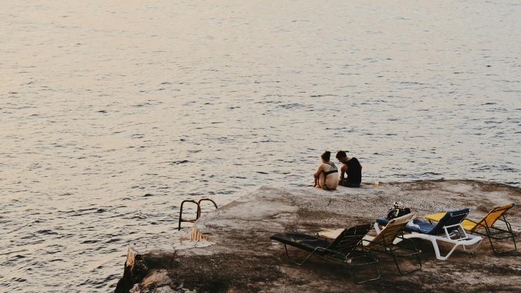 People sitting on a rock overlooking water